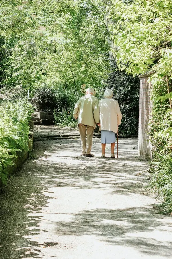 Two residents walking arm in arm along a garden path