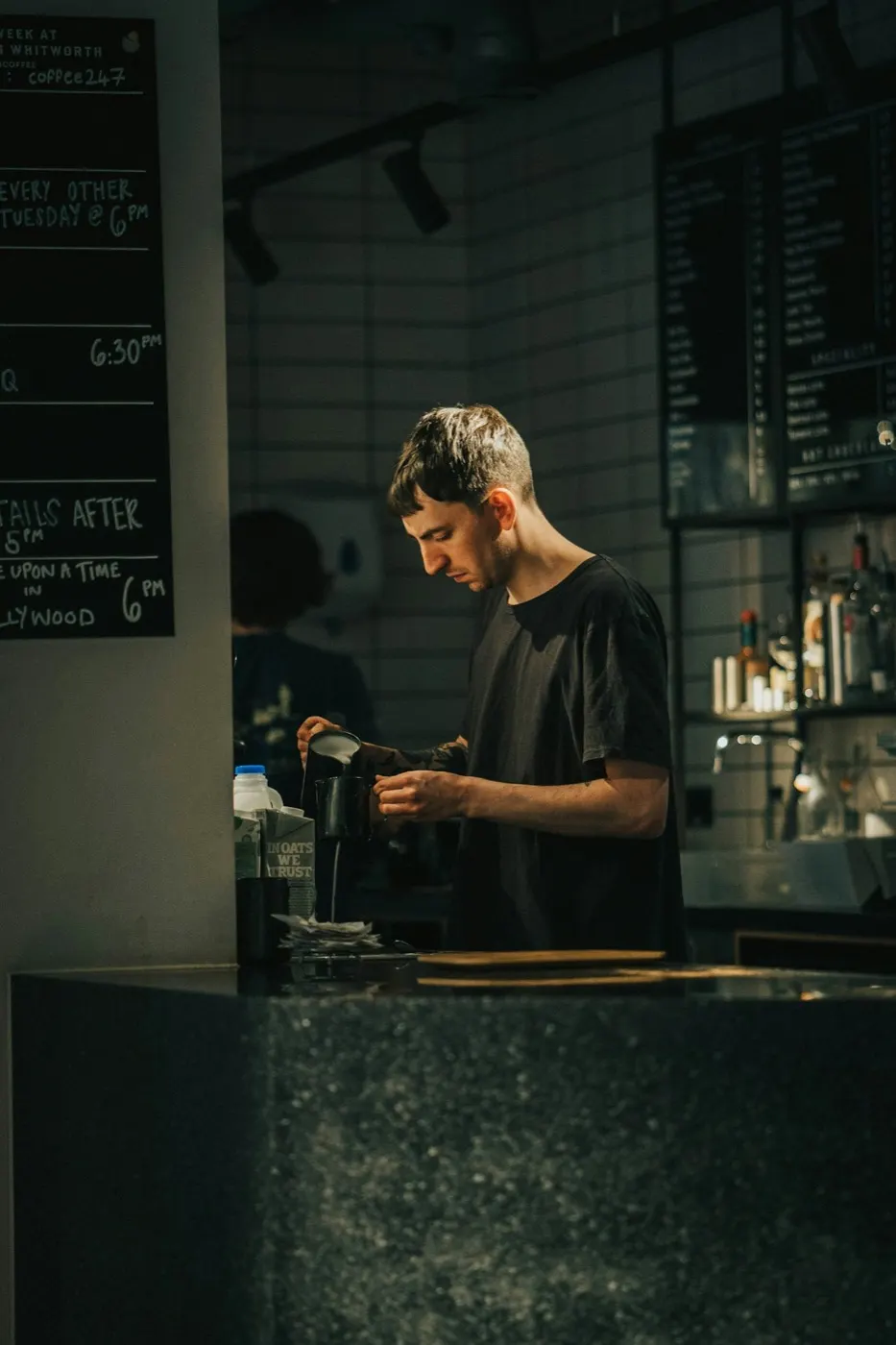 A bartender working at the counter of a small bar