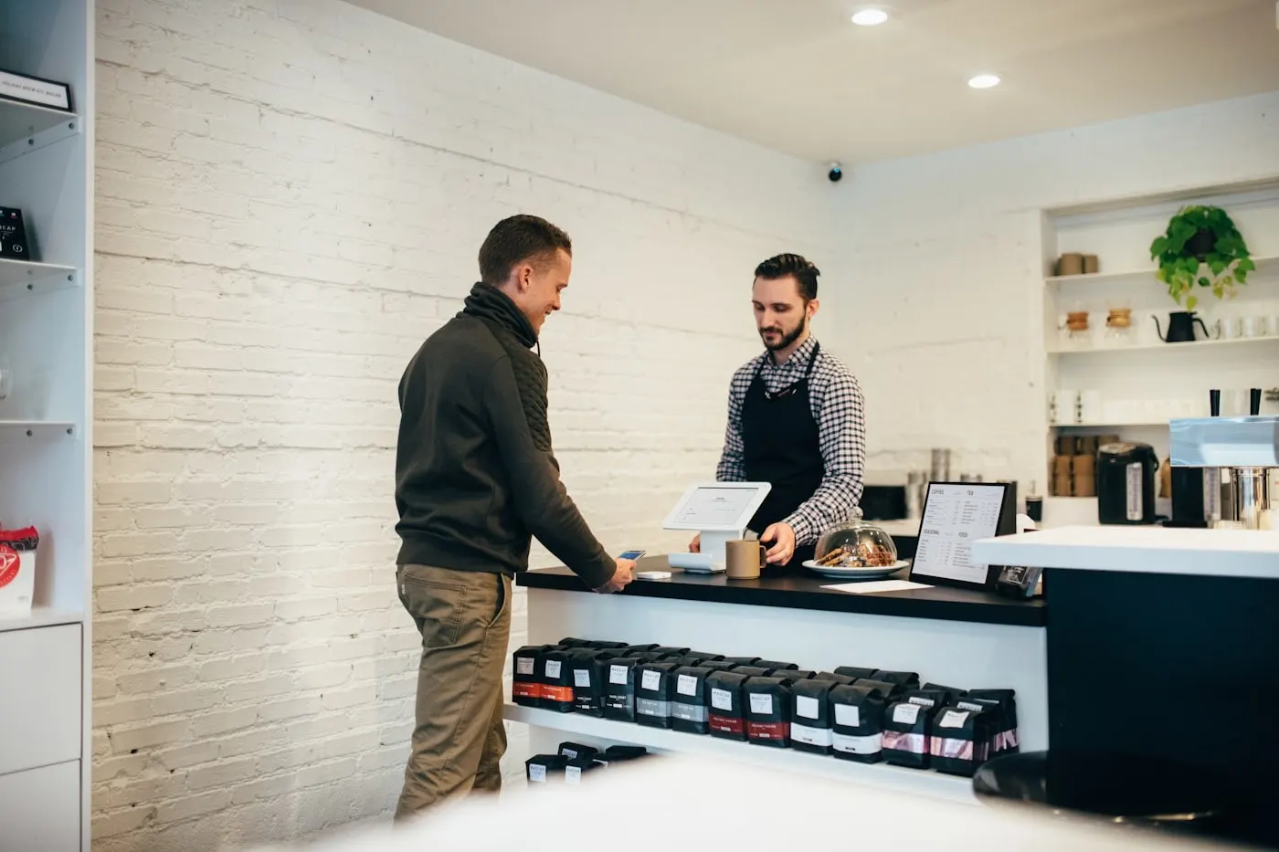 A barista serving a customer at the counter of a small cafe