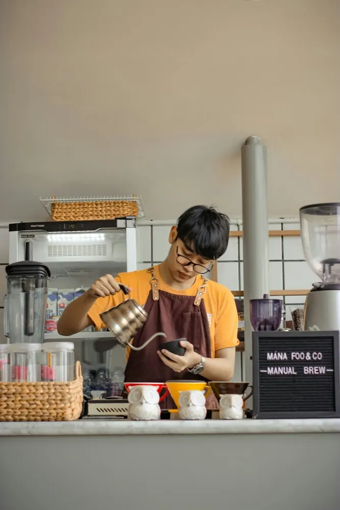 A barista pouring filter coffee behind a cafe counter