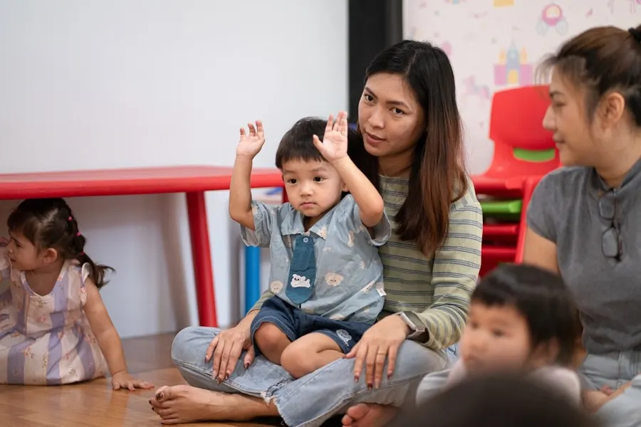 An educator sitting with toddlers at group time, one child with a hand raised