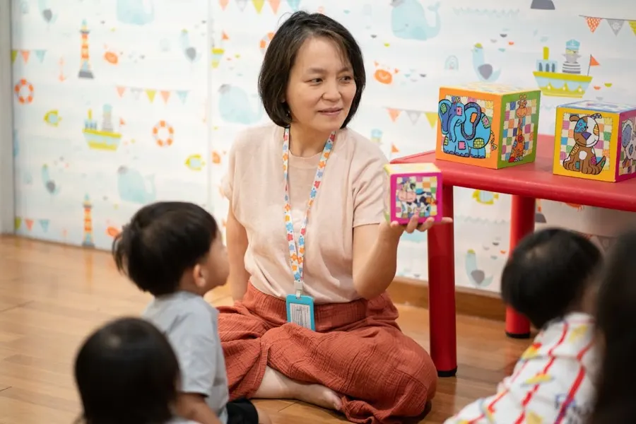An educator reading with a small group of toddlers on the floor