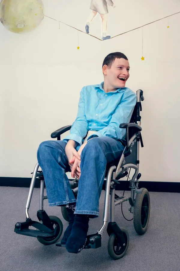 A young man in a wheelchair laughing indoors