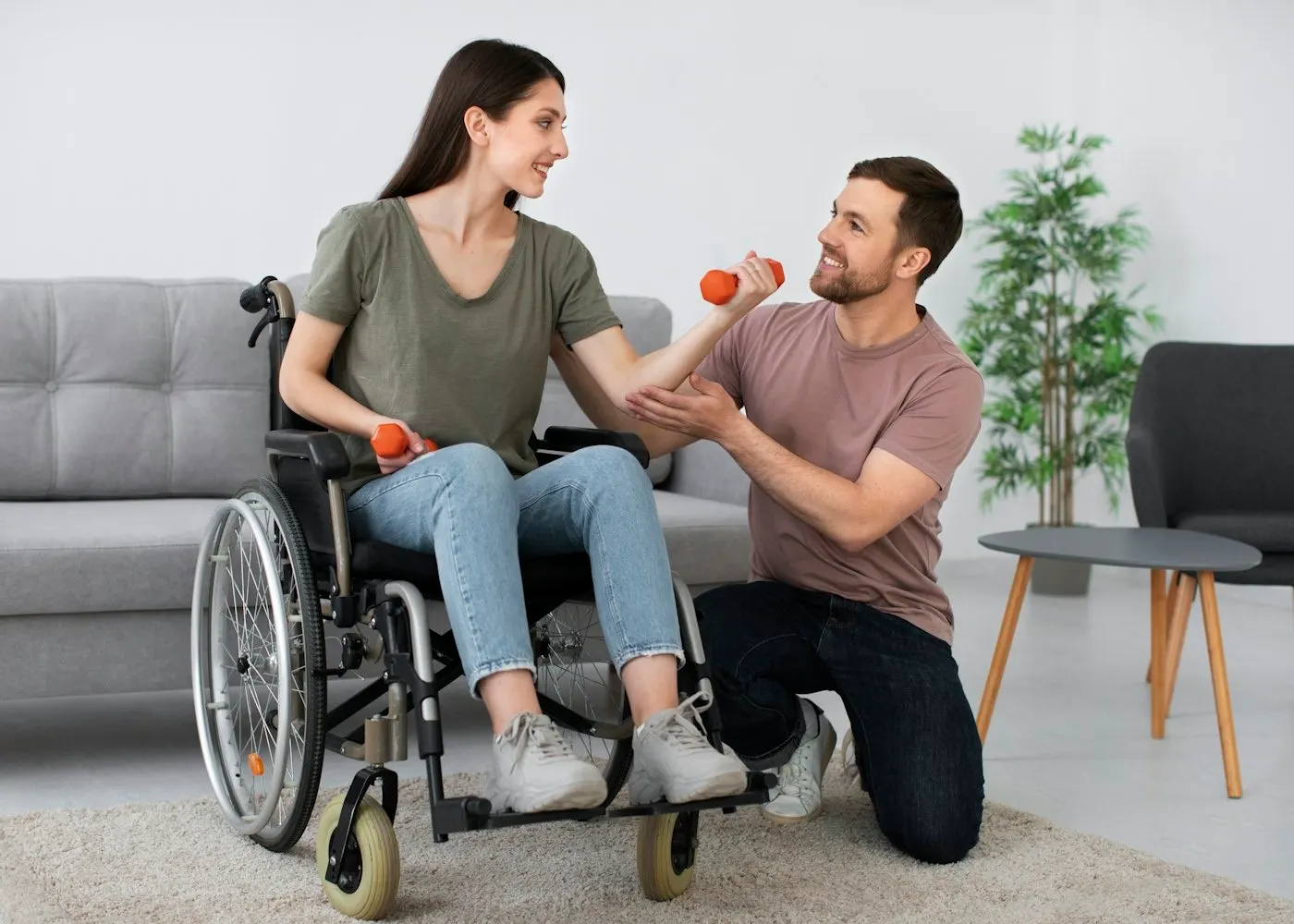 A support worker helping a woman who uses a wheelchair with light exercise at home